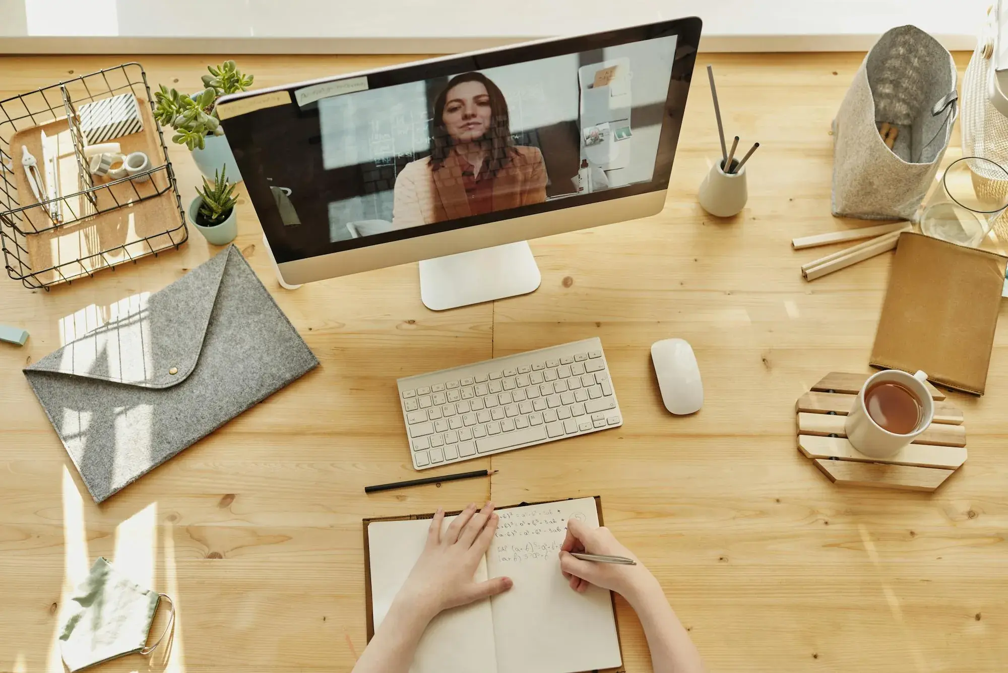 Top-down view of a study desk: laptop on a video call, notebook, coffee.