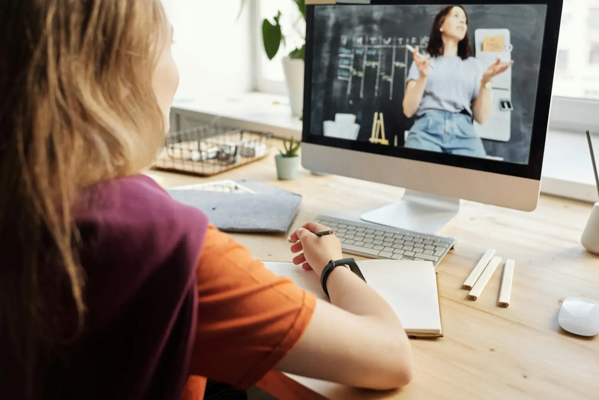 A learner watching a teacher explain a concept on a desktop monitor.